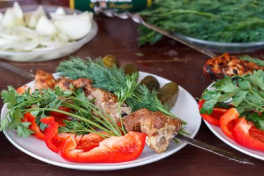 Beyaz tabakta taze sebzeler var, üzerinde et var.