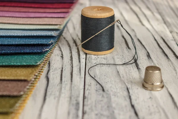 Amostras de tecido multicolorido. Um botão com uma agulha e um fio — Fotografia de Stock