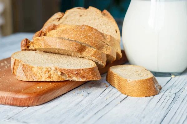 Stillleben mit Brotscheiben und Milch auf Holzgrund Stockfoto
