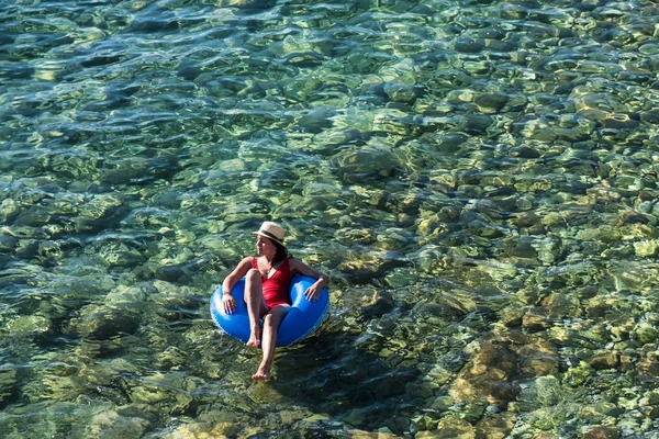 Hermosa joven con anillo inflable relajándose en el mar . — Foto de Stock