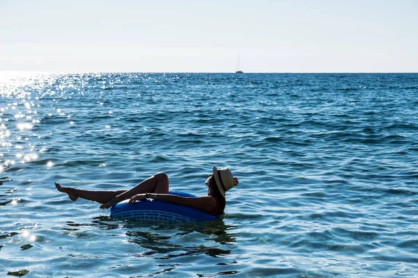 Hermosa joven con anillo inflable relajándose en el mar . — Foto de Stock
