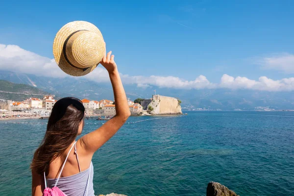 Vista trasera de una joven hermosa mujer en un sombrero mirando al casco antiguo de Budva, Montenegro — Foto de Stock