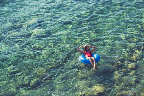 Vista aérea de la joven morena nadando en el gran círculo inflable en el mar turquesa . — Foto de Stock