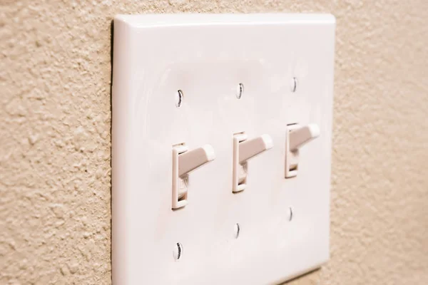 Traditional North American toggle white house electric light switch in ON position on aged old wood wall — Stock Photo, Image