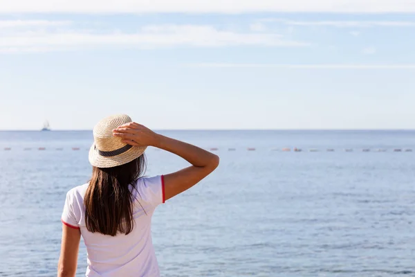 Hermosa chica mira al mar. Chica joven en un sombrero — Foto de Stock