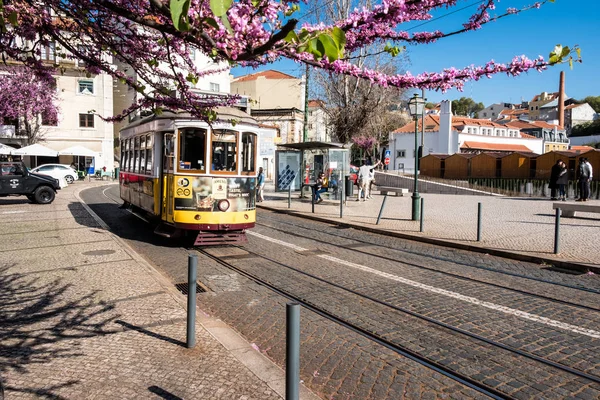 Lisbona, Portogallo - 23 marzo 2019: tram giallo, simbolo di Lisbona in strada soleggiata con turisti a piedi — Foto Stock