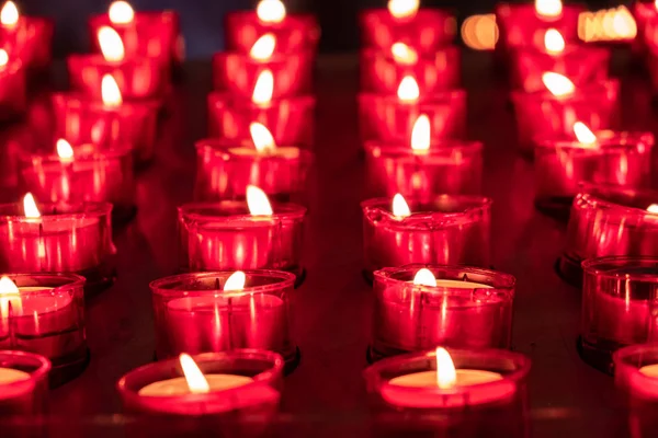Velas rojas brillando en la oscuridad. Tomado en ambiente religioso —  Fotos de Stock