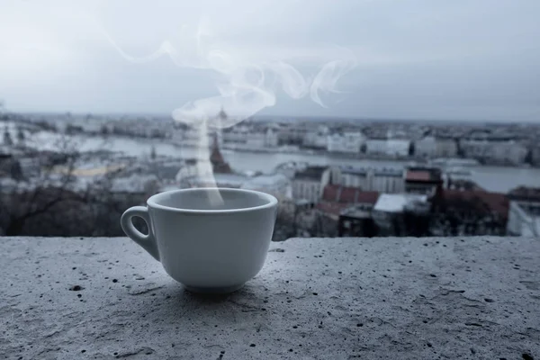 Close up white coffee cup on balcony over blurred view of city building. City skyline panorama — Stock Photo, Image
