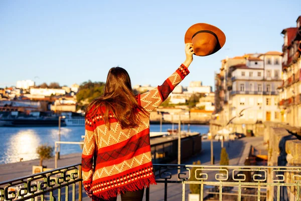 Mujer joven con el pelo largo caminando por la calle de la ciudad al amanecer, vistiendo sombrero y abrigo, disfrutando feliz momento agradable de sus vacaciones — Foto de Stock