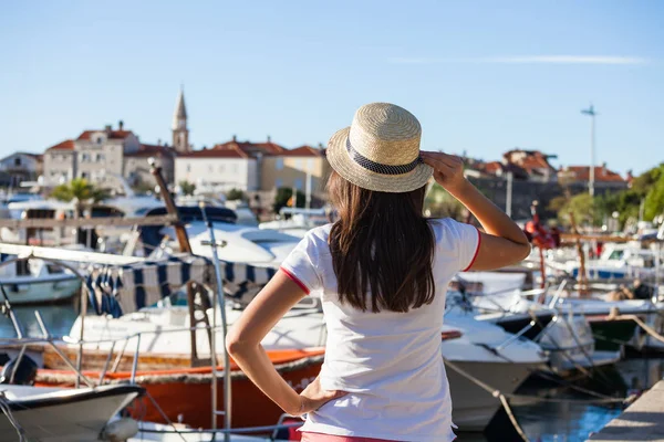 Hermosa joven con sombrero de pie cerca de los barcos en el puerto deportivo de la ciudad mediterránea . — Foto de Stock