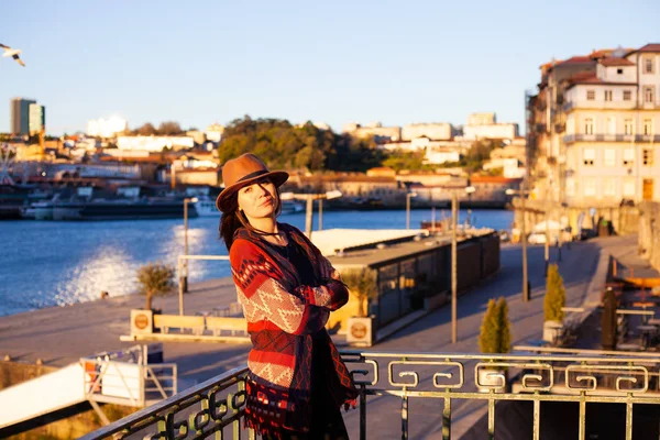 Mujer joven con el pelo largo caminando por la calle de la ciudad al amanecer, vistiendo sombrero y abrigo, disfrutando feliz momento agradable de sus vacaciones — Foto de Stock