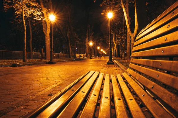 Noční městský park. Dřevěné lavičky, pouliční osvětlení a parková ulička — Stock fotografie