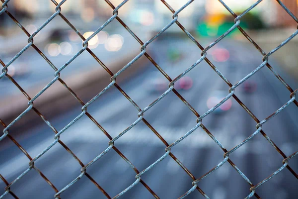 Stadens silhuett genom wire mesh stängslet. Abstrakta suddig stadsbilden bakgrund — Stockfoto