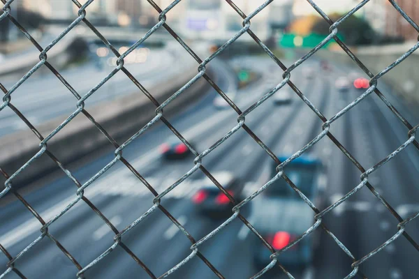 City skyline through the wire mesh fence. Abstract blurred cityscape background — Stock Photo, Image