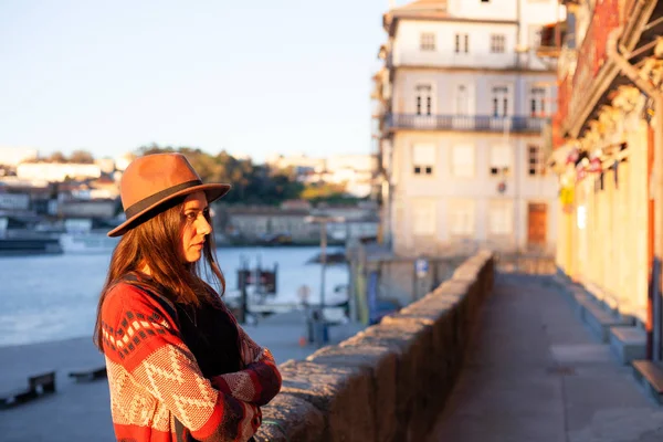 Mujer joven con el pelo largo caminando por la calle de la ciudad al amanecer, vistiendo sombrero y abrigo, disfrutando feliz momento agradable de sus vacaciones — Foto de Stock