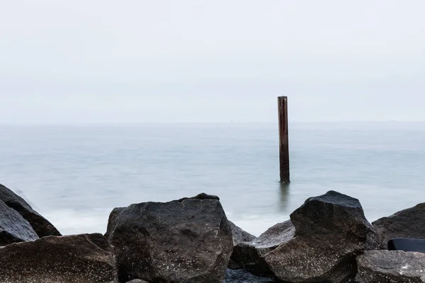 Long exposure minimalistic photo of sea and rocks. Stone breakwater — Stock Photo, Image