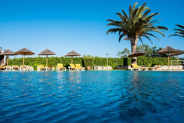 Kaunis trooppinen ranta edessä hotelli keinona uima-allas, aurinko-loungers ja palmuja lämpimänä aurinkoisena päivänä . — kuvapankkivalokuva