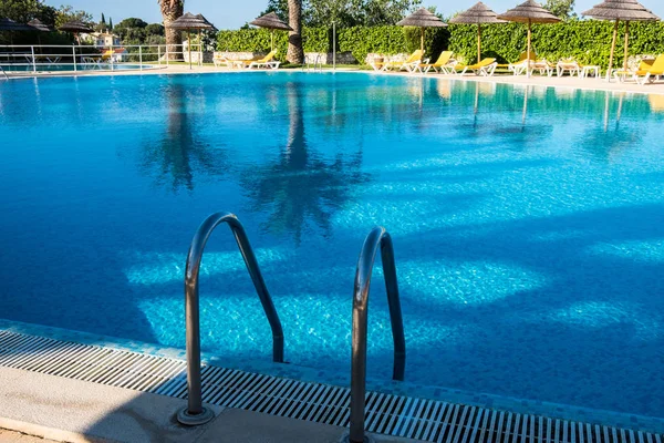 Hermoso complejo hotelero frente a la playa tropical con piscina, tumbonas y palmeras durante un cálido día soleado . — Foto de Stock