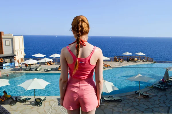 여자는 분홍색 셔츠에 머리와 일광욕 이집트에서 따뜻한 리조트에서 바다와 수영장의 — 스톡 사진