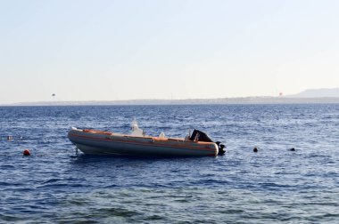 Şişme bir gri tekne, bir arka plan şamandıralar ve uzak dağlar ve mavi gökyüzü bir tropikal tatil tuz mavi denizde bir motor ile bir motorlu tekne.