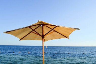 Güneşten koruyan güzel doğal şemsiyeler mavi gökyüzüne karşı kurutulmuş dallardan sarı kumaştan yapılmış, cennet tropikal dinlenmek tesisi ve kopya alanı tuz deniz.