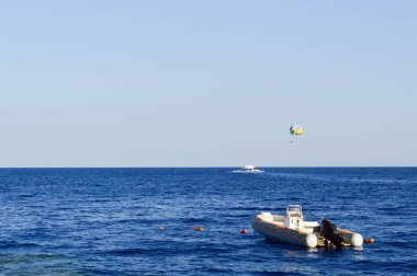 Helisel motor paraseyling ve mavi gökyüzü bir çerçevede bir tuz güzel denizde şişme bir gri motorlu tekne.