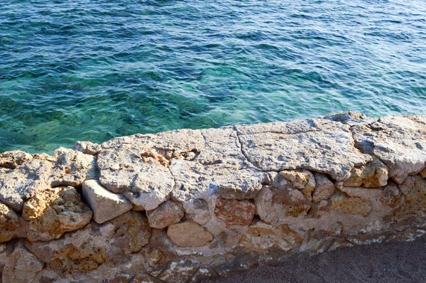 青い海の上からの眺め 石畳の石の古い古代崩壊壁からのサンゴ底を持つ水 — ストック写真
