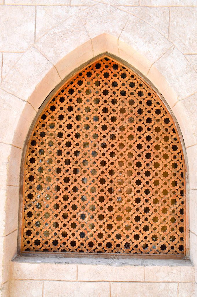 The texture of the brick wall and the wooden brown old man of the ancient carved Arab Islamic Islamic triangular window with ornaments and patterns with holes in the form of stars. The background.