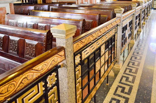 棕色坚固的木制长凳 座椅与金色扶手和装饰品在教堂与雕刻图案的祈祷 — 图库照片