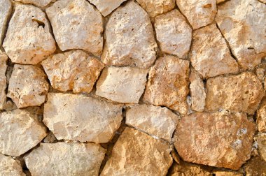 Düzensiz farklı antik kayrak taşları kumlu dikişleri ile farklı formlarının Mevduatı deniz tuzu ile eski bir taş sarı duvardan doku. Arka plan.