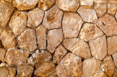 Düzensiz farklı antik kayrak taşları, kumlu dikişleri ile çeşitli şekillerde cobblestones Mevduatı deniz tuzu ile eski bir taş sarı duvardan doku. Arka plan.