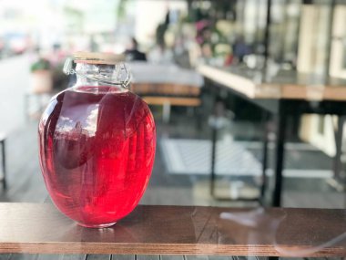 Büyük güzel üç litrelik cam banka bir jambon, suyu, iksir bulanık bir arka planda bir raf ahşap kapaklı parlayan bir sıvı ile.