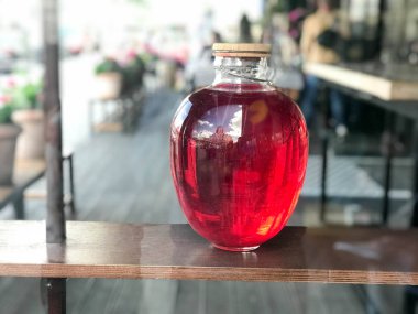 Kırmızı büyük cam üç-litre parlayan banka bir başlık, suyu, iksir bulanık bir arka plan üzerinde ahşap kapaklı.