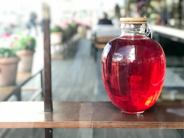 Büyük bir cam üç-litre olabilir campote, suyu, iksir bulanık bir arka plan üzerinde ahşap kapaklı parlayan bir sıvı ile.