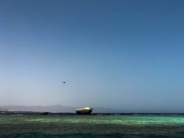 Büyük bir gemi, bir liner, bir tanker mercan resifleri ve bir helikopter üzerinde bir kaza sonra kırık mavi bir tuzlu denizin güzel bir tropikal manzara karşı.