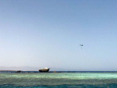 Büyük bir gemi, bir liner, bir tanker mercan resifleri ve bir helikopter üzerinde bir kaza sonra kırık mavi bir tuzlu denizin güzel bir tropikal manzara karşı.