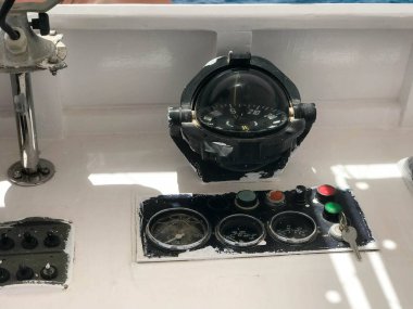 Gösterge paneli olan bir tekne, gemi, yuvarlak siyah pusula, bir takometre, bir hız göstergesi, bir kontak anahtarı ve düğmeler büyük bir cam ile deniz taşımacılığı.