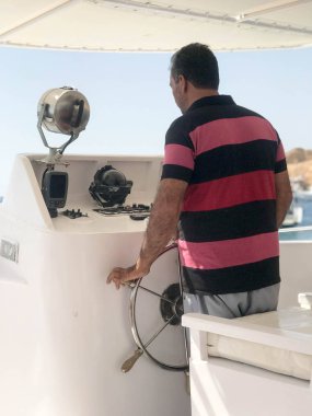 Tekne, tekne dümen kırmızı çizgili tişört erkekte yağız kaptanı yönetir.