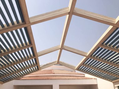 Modern tasarımcı trendy üçgen çatı, güneşte tahtaları ile kirişler delikleri ile açık gölgelik.