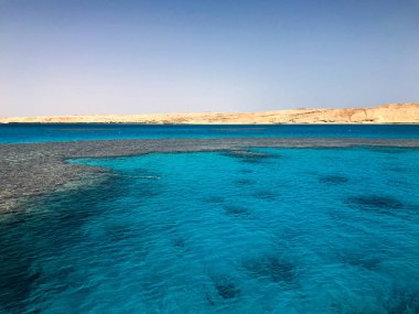 Manzara saydam mavi deniz tuzlu su, deniz, okyanus dalgaları ile bir alt güzel mercan resifleri ile periling sarı arka planı taş taş uzak dağlar.