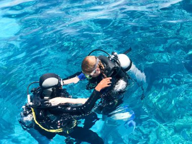 İki dalgıçlar siyah tüplü dalış takım elbise, bir adam ve bir kadın oksijen şişe ile lavabo şeffaf mavi su deniz, okyanus bir tropik cennet sıcak tatil altında.