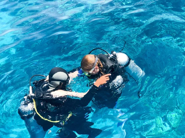İki dalgıçlar siyah tüplü dalış takım elbise, bir adam ve bir kadın oksijen şişe ile lavabo şeffaf mavi su deniz, okyanus bir tropik cennet sıcak tatil altında.
