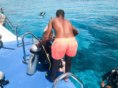 Dalgıçlar siyah tüplü dalış takım elbiseli oksijen şişeleri alıcıları şeffaf mavi su denizin altında ile bir siyah, yağız, Arap atletik atletizm adam yardım, bir tropik cennet okyanusta sıcak resort.