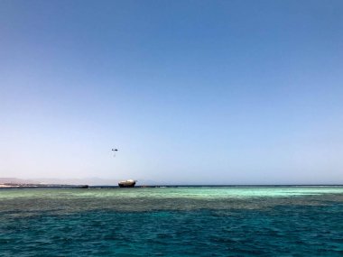 Tropik sahil beldesi ve bir gemi, bir tekne, bir tanker ve bir helikopter enkazı sitede mavi tuz deniz manzaralı güzel bir deniz manzarası.