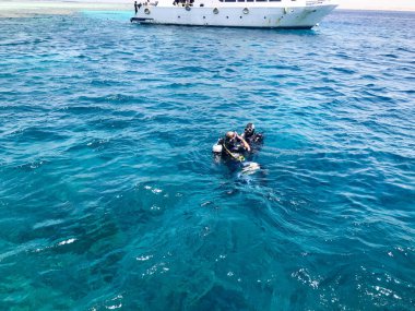 İki dalgıçlar siyah parlak metal alüminyum oksijen silindir ile su geçirmez takım elbise dalış yüzmek, tatil, bir tekne, bir gemi arka planda bir seyir mavi deniz suda bırakın.