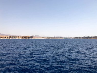 Uzak güzel kahverengi taş dağlar ve kıyı ve mavi tuz Azure deniz üzerinde binalar Seascape, mavi gökyüzüne karşı okyanus.