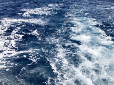 İçten içe kaynıyordu mavi doku deniz tuzlu su dalgalar, dökülmeleri, bubbles, köpük, izler sonra hızlı bir kayan sepeti, mavi gökyüzü karşı bir tekne.