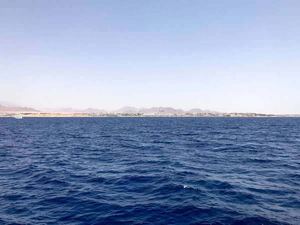 Uzak güzel kahverengi taş dağlar ve mavi tuz Azure deniz, okyanus mavi gökyüzüne karşı deniz manzara.