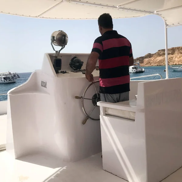 Eski esmer Arap Müslüman geminin kaptanı kırmızı çizgili gömlekli Tamam, bir tekne, bir cruise gemisi denizde, sıcak bir tropikal resort Mısır'ın yönetiminde duran bir gemiyi kontrol ediyor..