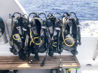 Hortumlar ve dalgıç ceket asmak hızlı hareket eden bir teknede bir stand ile siyah dalış takım elbiseli bir sürü gemi, cruise liner bir tropikal tatil mavi denize karşı.